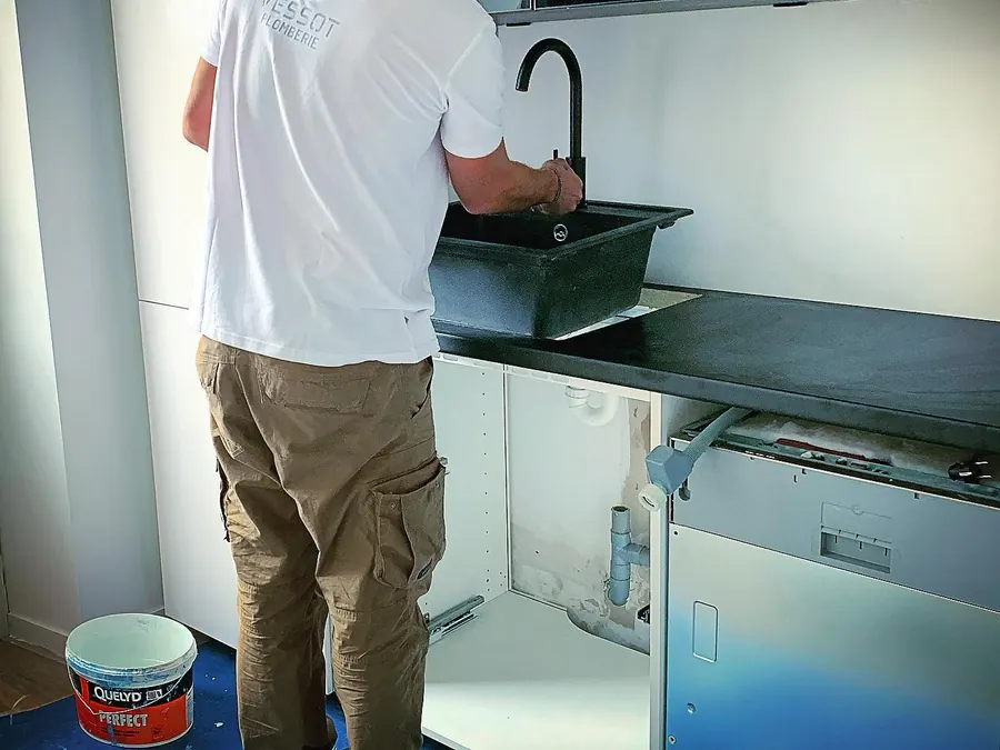Artisan de VESSOT PLOMBERIE posant un évier dans une cuisine