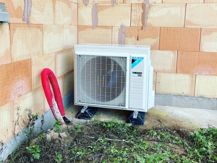 Unité extérieure de pompe à chaleur Daikin installée contre une maison neuve