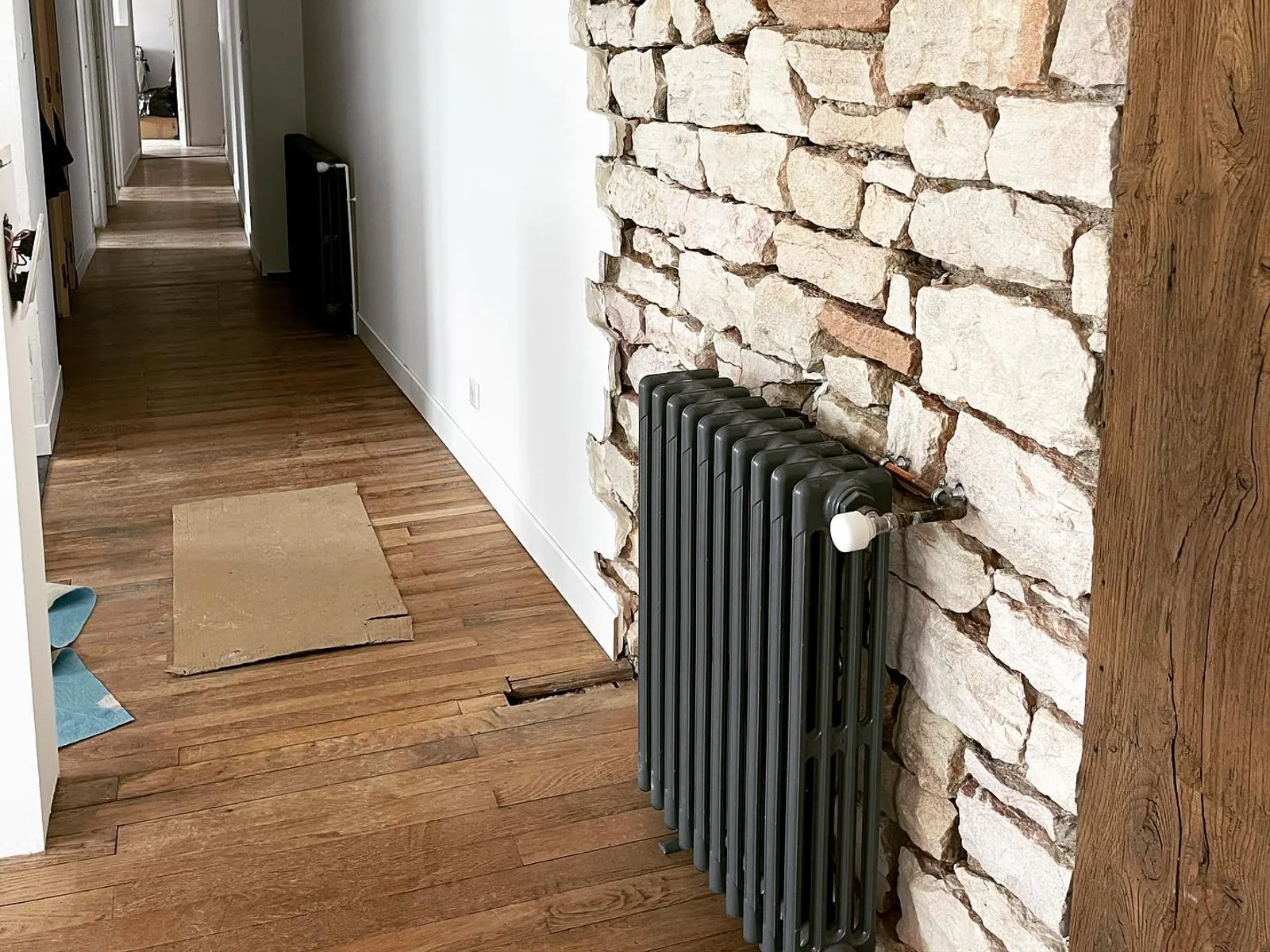 Radiateur en fonte posé contre un mur de pierre à Lugny